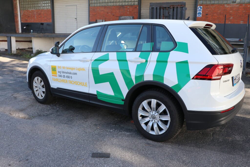 Weiße und grüne Fahrschulfahrzeug, Rückansicht, auf einem Parkplatz geparkt.